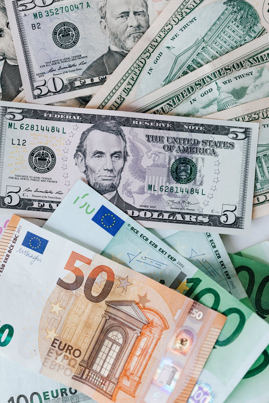 stack of different currency with photo of men and buildings